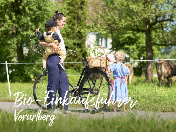 © Ivo Vögel Junge Frau mit Kind auf dem Arm & Einkaufskorb und Fahrrad vor einer Weide