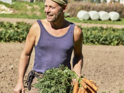 Gemüsebauer am Feld mit Karotten in der Hand