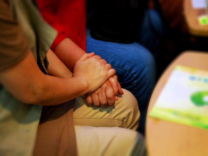 Mann und Frau halten sich an der Hand - sitzend