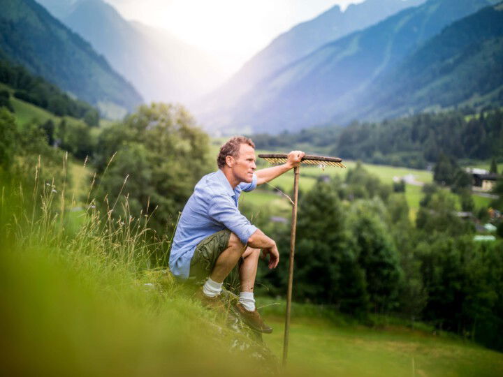 Bauer mit Rechen in den Bergen