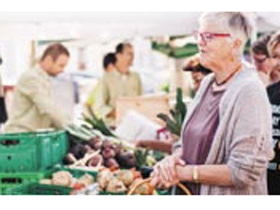 Frau kauft am Markt Gemüse
