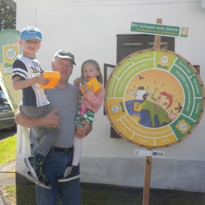 Vater mit Kindern im Arm vor dem Bio-Glücksrad am Biofest in Langeck 2017