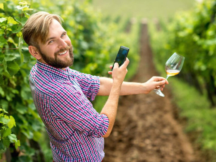 Weinbauer mit Weinglas und Smartphone