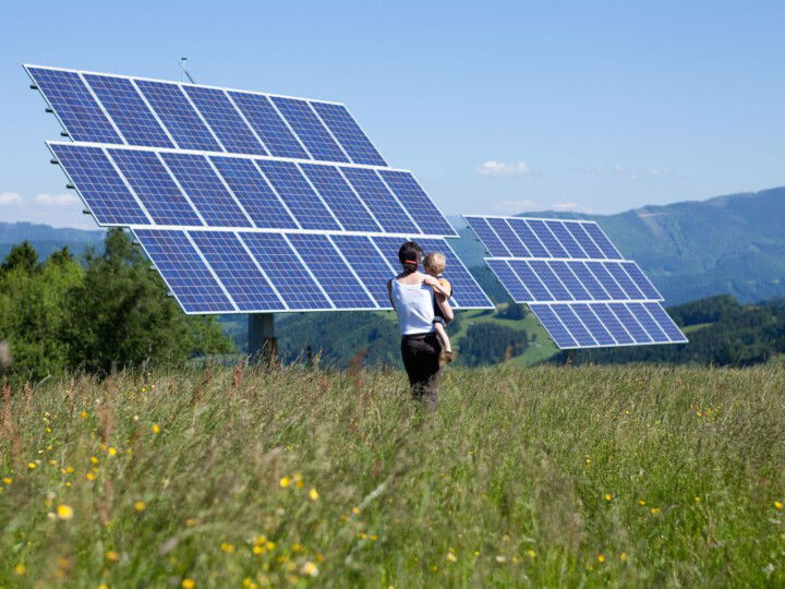 Mutter mit Kind im Arm vor Solaranlage